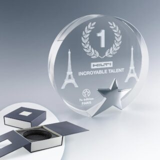 Trophée rond en verre avec étoile métallique et gravure laser personnalisée, livré dans un coffret rigide.