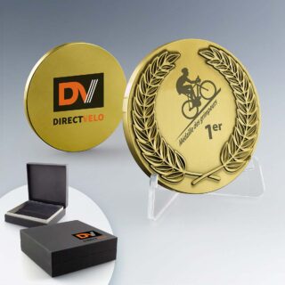 Médaille dorée ronde avec une couronne de lauriers en relief et une personnalisation centrale en impression numérique couleur affichant le logo d'une entreprise de cyclisme et une inscription "Médaille des grimpeurs 1er".
