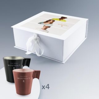 Coffret blanc avec ruban contenant quatre tasses expresso en verre, deux noires et deux terracotta, sur un fond gris.