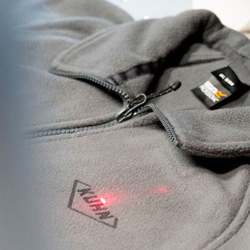 Gravure laser sur textile : logo en cours de marquage sur une veste polaire grise.