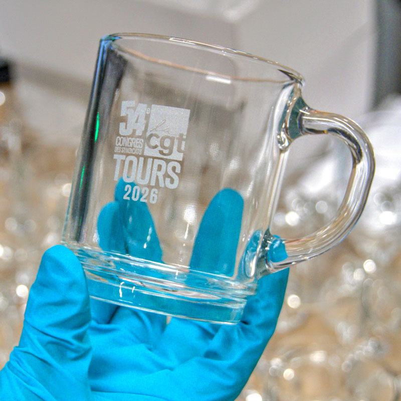 Mug en verre gravé pour le 54e congrès de la CGT à Tours en 2026, tenu dans une main gantée.