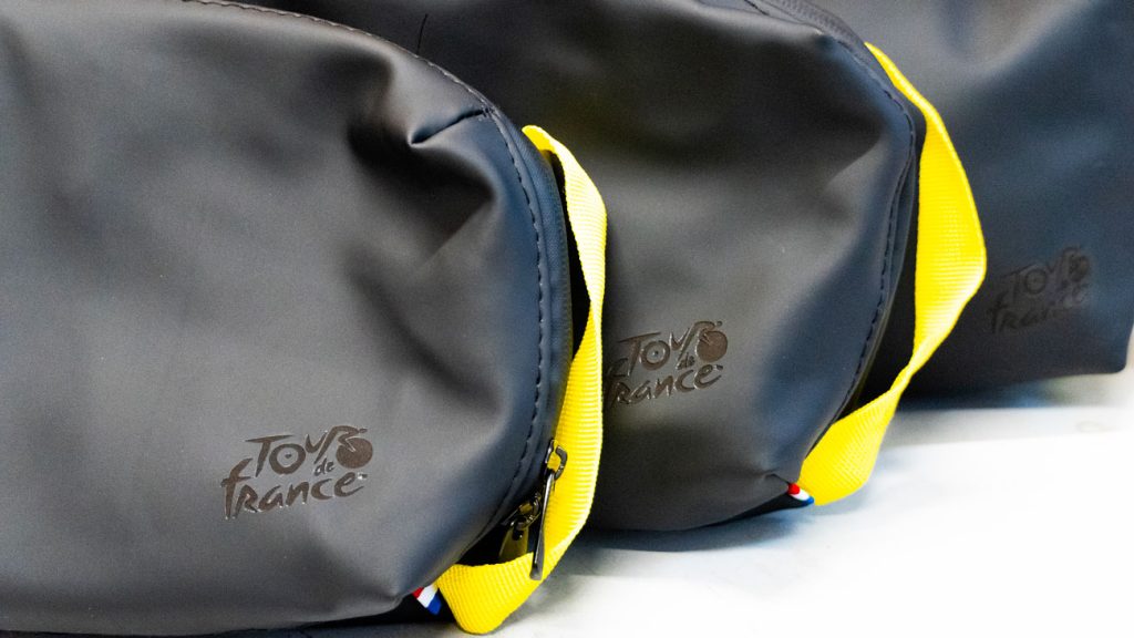 Sacs gris à sangles jaunes personnalisés avec le logo Tour de France gravé sur leur face avant.