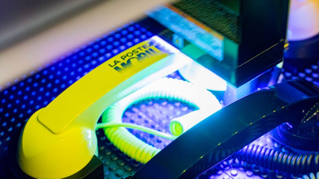 Impression numérique sur objets : marquage du logo La Poste Mobile sur un combiné téléphonique jaune.